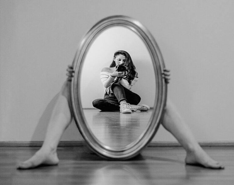 a woman sitting on the floor looking at her reflection in a mirror